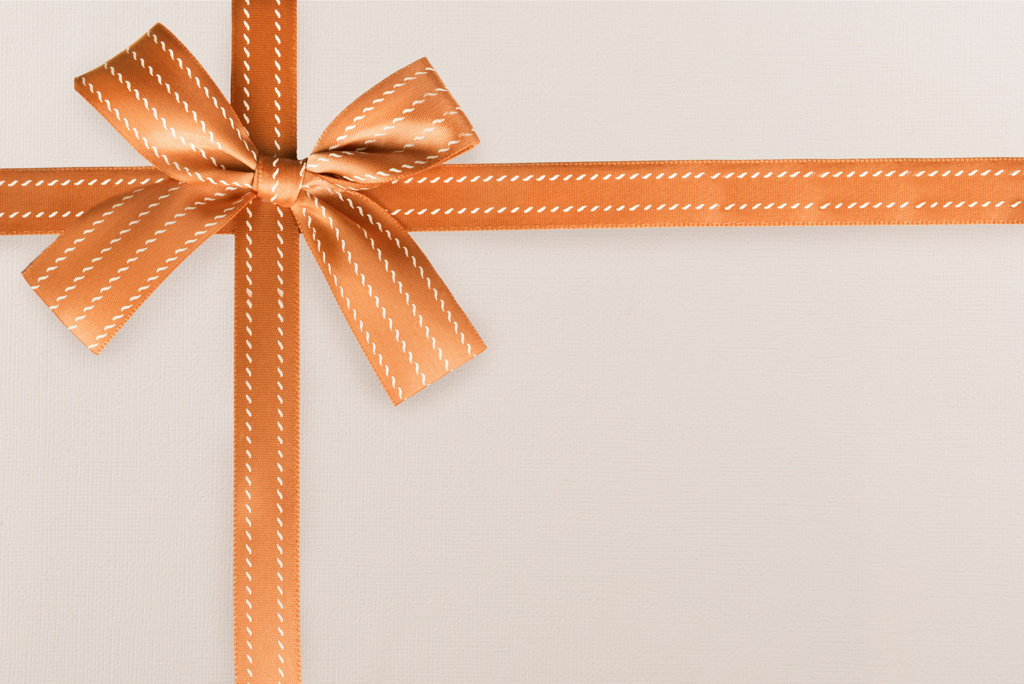 Orange Gift Ribbon and Knot on a White Textured Pattern in Background. Gift Box Wrapping Concept.
